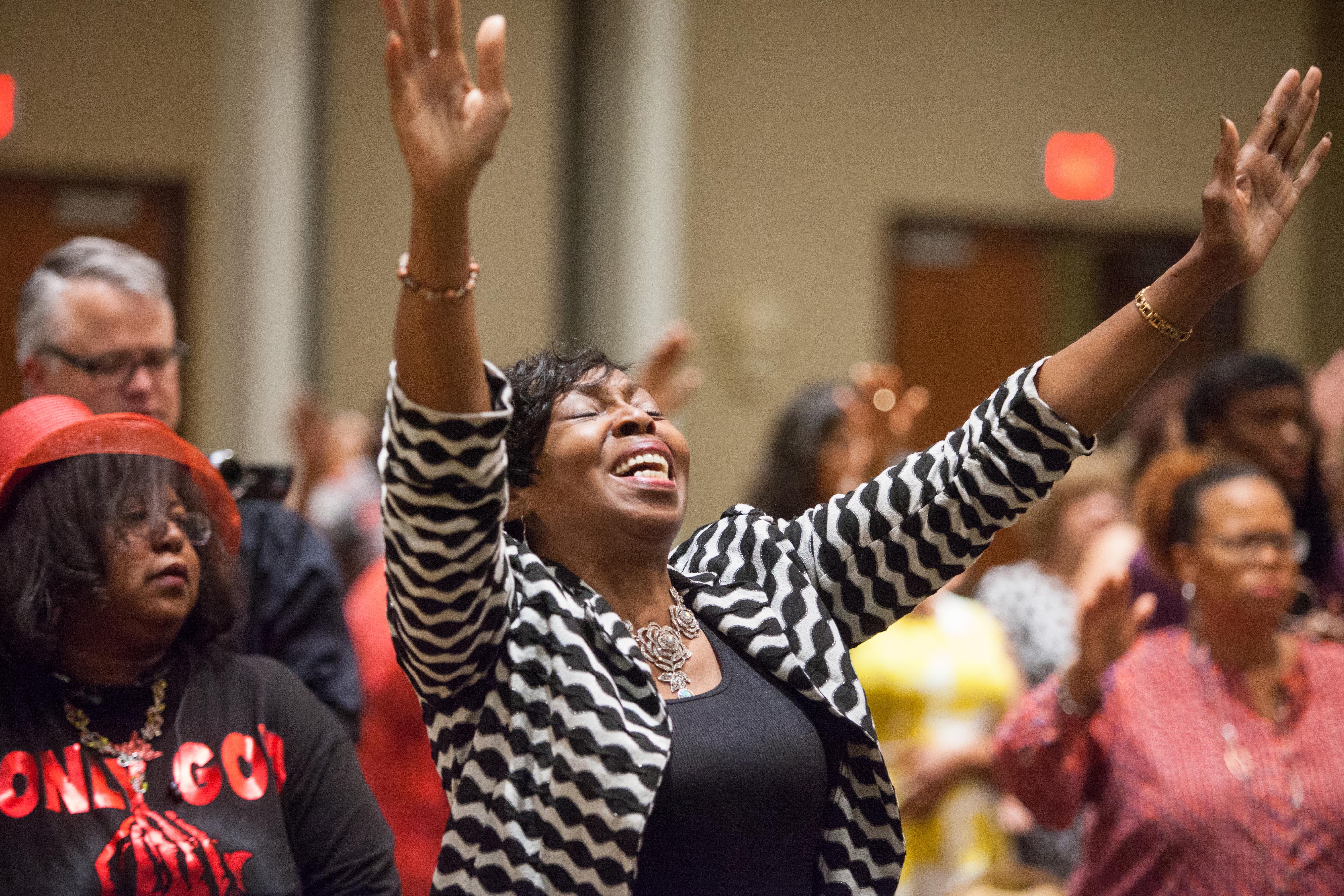 A woman uplifts her hands in total praise