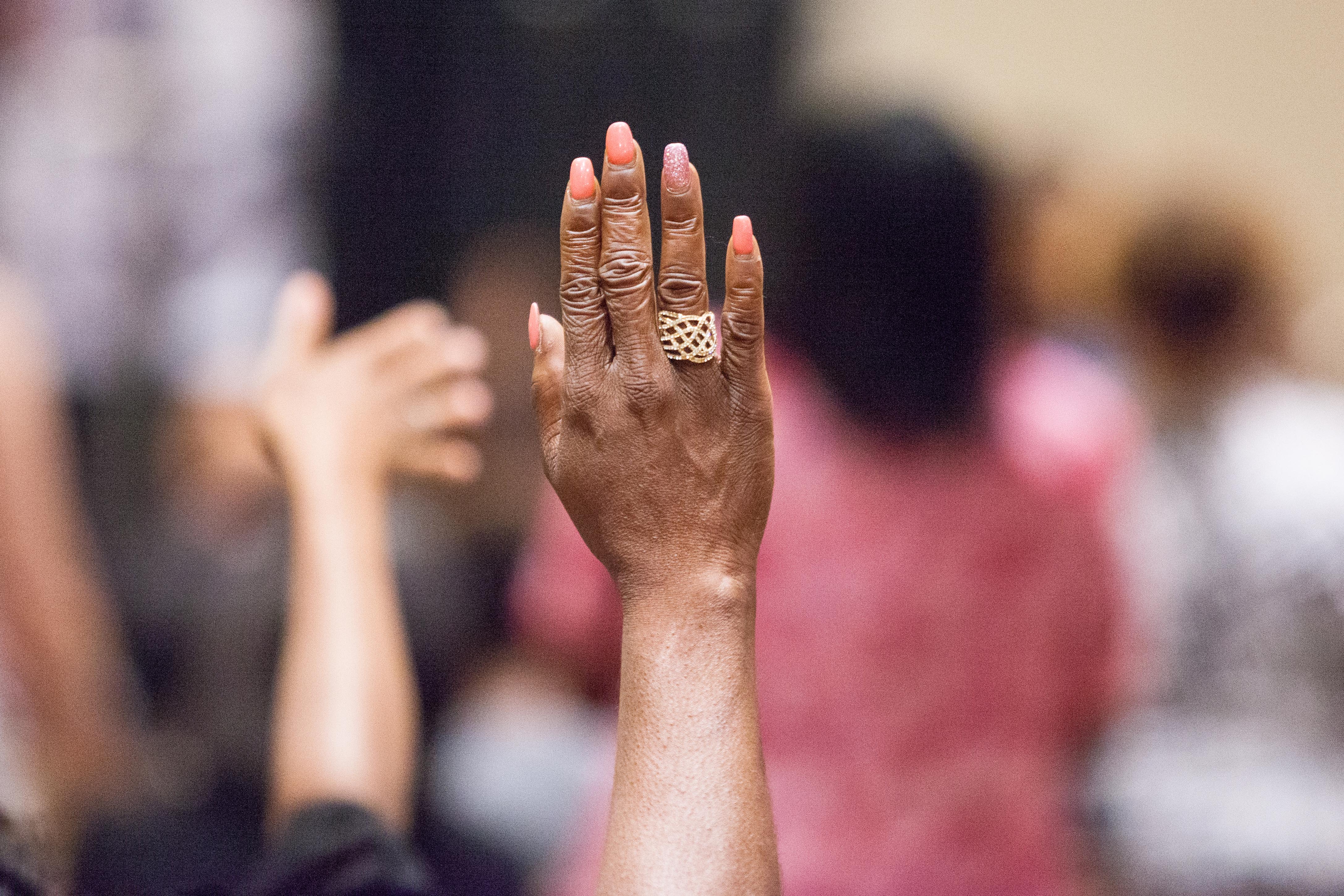 A hand with a ring is raised in praise