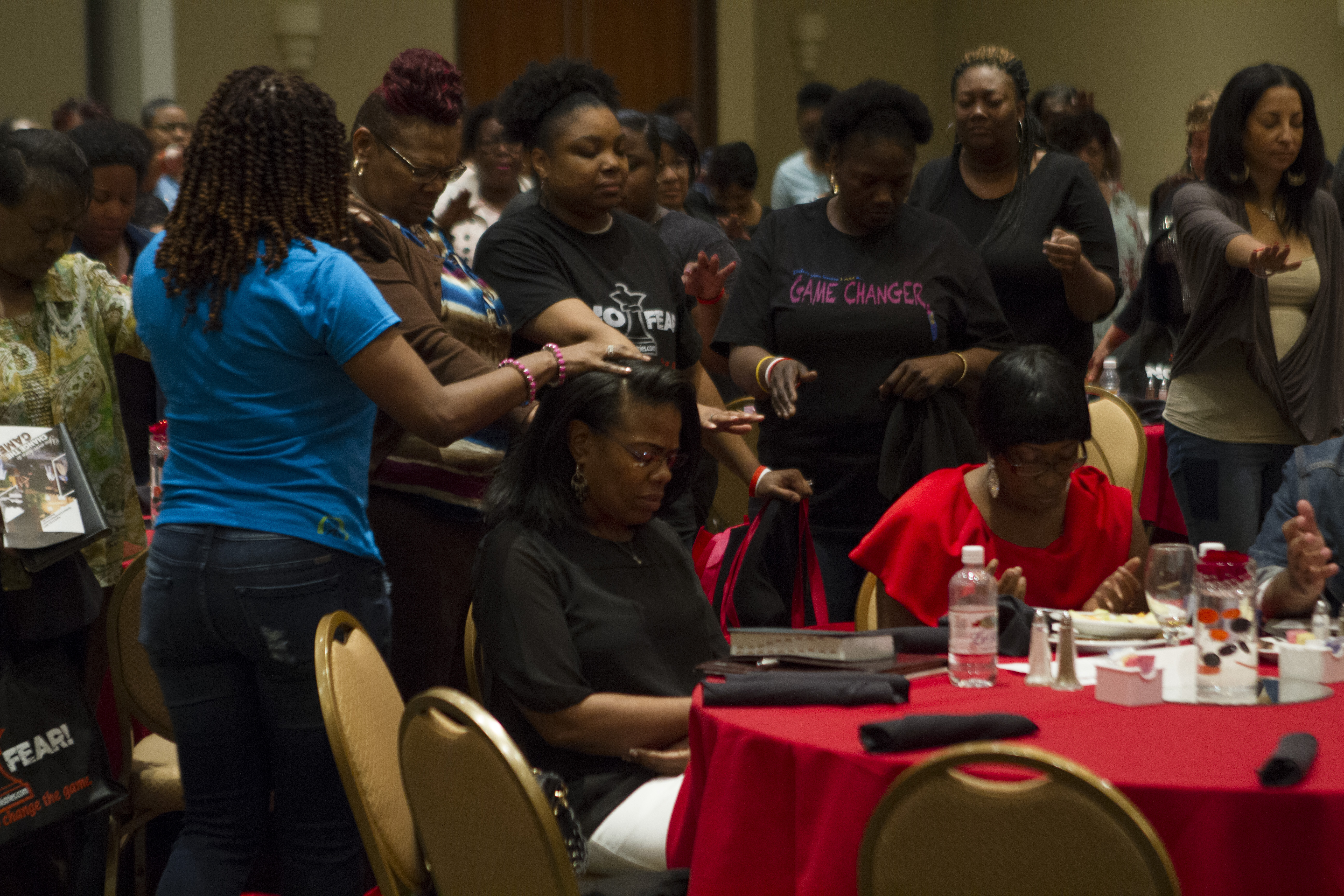 Women lay hands on a woman in prayer and petition
